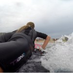 girl laying on surfboard as she gets ready to stand up on the board