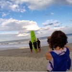 Woman taking a picture of 3 boys in front of green surfboard
