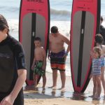 group of kids posing next to two surfboards