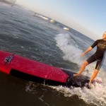girl standing at the back of the surfboard balancing