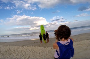 Woman taking a picture of 3 boys in front of green surfboard