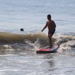 Young boy surfing small wave with three people around