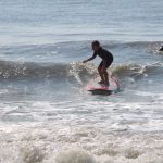 Boy rides a wave as instructor watches in the water