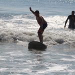 boy has one arm up as he finishes surfing a wave