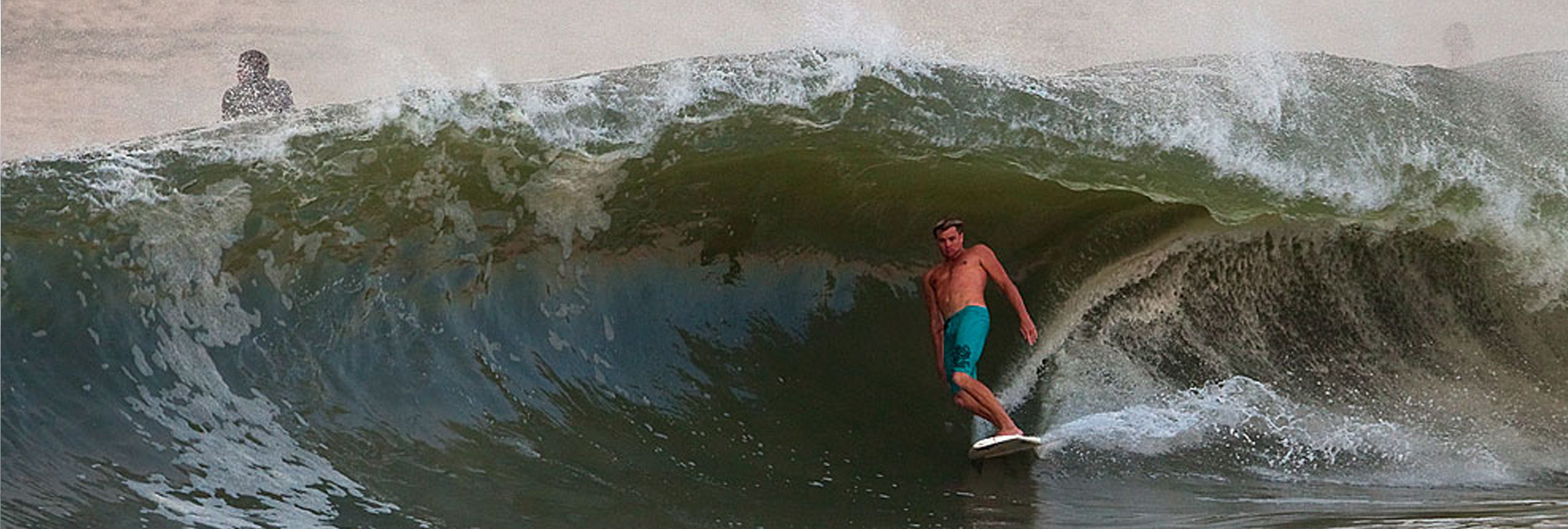 man surfing a huge wave in blue bathing suit
